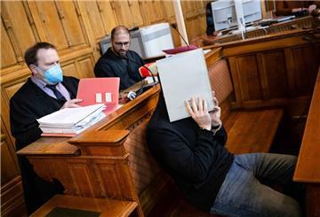Der Angeklagte im Gerichtssaal. Hinter ihm sitzen seine beiden Anwälte.