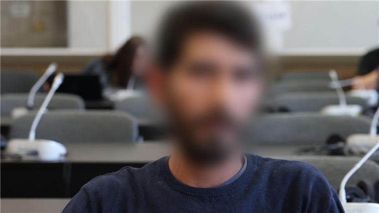 Der Angeklagte sitzt kurz vor Beginn der Verhandlung in einem Gerichtssaal.