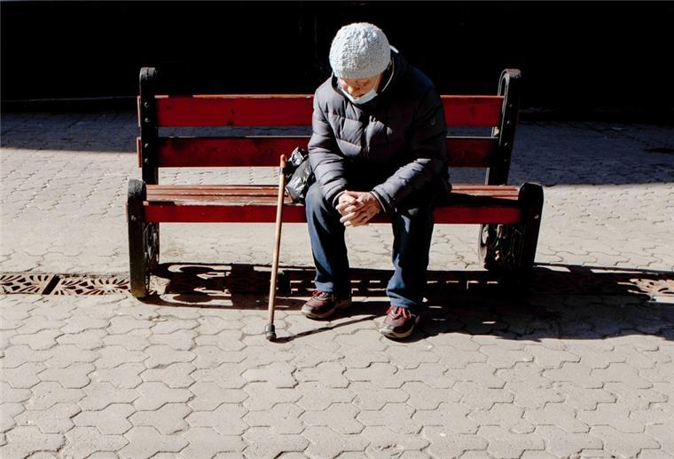 Bericht: Ältere sind seit Corona-Pandemie einsamer Eine ältere Frau mit Mund-Nasen-Schutz sitzt auf der Bank.