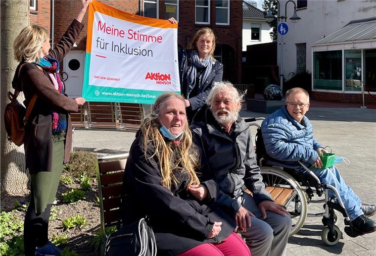 Der Banner wird von den Organisatoren der Aktion, Xenia Wakengut (links) und Anne Blankemeyer vom Fachdienst Teilhabe des Sozialwerks Wesermarsch, gehalten. Auf der Bank sitzt die Bewohnervertretung der Sozialstation Wesermarsch (vorne links): Beate Bartels, Peter Heuer und Frank Becke.