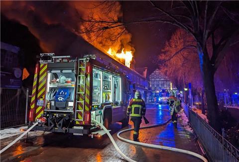 Feuerwehrauto steht vor brennendem Haus