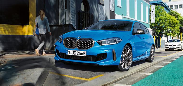 Exklusive Doppelpremiere am Samstag: Alle sind herzlich eingeladen Blauer BMW 1er auf einer sonnigen Straße