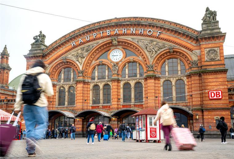 Reisende bewegen sich auf dem Vorplatz des Bremer Hauptbahnhofs auf das Gebäude des Bahnhofs zu.  