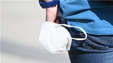 Ein Mann trägt eine Maske in der Hand.