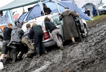 Festivalbesucher schieben auf dem Campingplatz des Wacken Open Air Festivals (Kreis Steinburg) ein Auto aus dem Schlamm