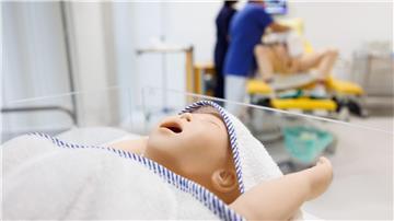 Der Dummy eines Säuglings liegt in einem Bettchen im Simulationslabor vom Studiengang Hebammenwissenschaft.