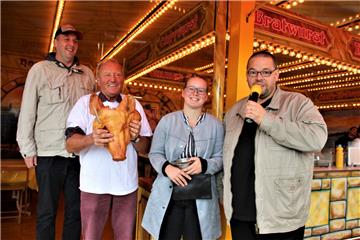 Der erste Schweinskopf ging schnell an den Mann. Das Foto zeigt (von links) Gewinner Stefan Hülstede, den früheren Schlachtermeister Hans-Jürgen Kaliwoda, die Auszubildende bei der Gemeindeverwaltung Charlotte Schmidt, die Geld einsammelte, und Versteigerer Andreas Decker.