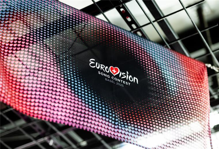 700 freiwillige Helfer für den Eurovision Song Contest gesucht Eine Fahne mit dem offiziellen Design des Eurovision Song Contest (ESC) 2025 hängt in einem Club in Basel.
