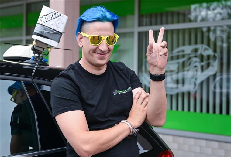 Livestream aus dem Auto: Fahrlehrer überträgt Anfängerstunden im Netz Der Fahrlehrer Fabian Schittenhelm steht an einem Schulfahrzeug gelehnt.