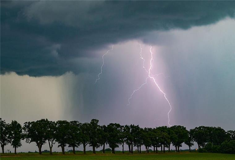 Gewitter, Sturm und Hagel! Kaltwetter-Front erreicht die Nordseeküste Ein Blitz leuchtet am späten Abend über der Landschaft.
