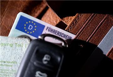 Ein Führerschein, ein Autoschlüssel und eine Zulassungsbescheinigung liegen auf einem Portemonnaie. 