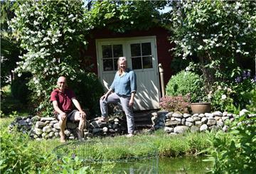 Mann und Frau vor einer Hütte in einem Garten.
