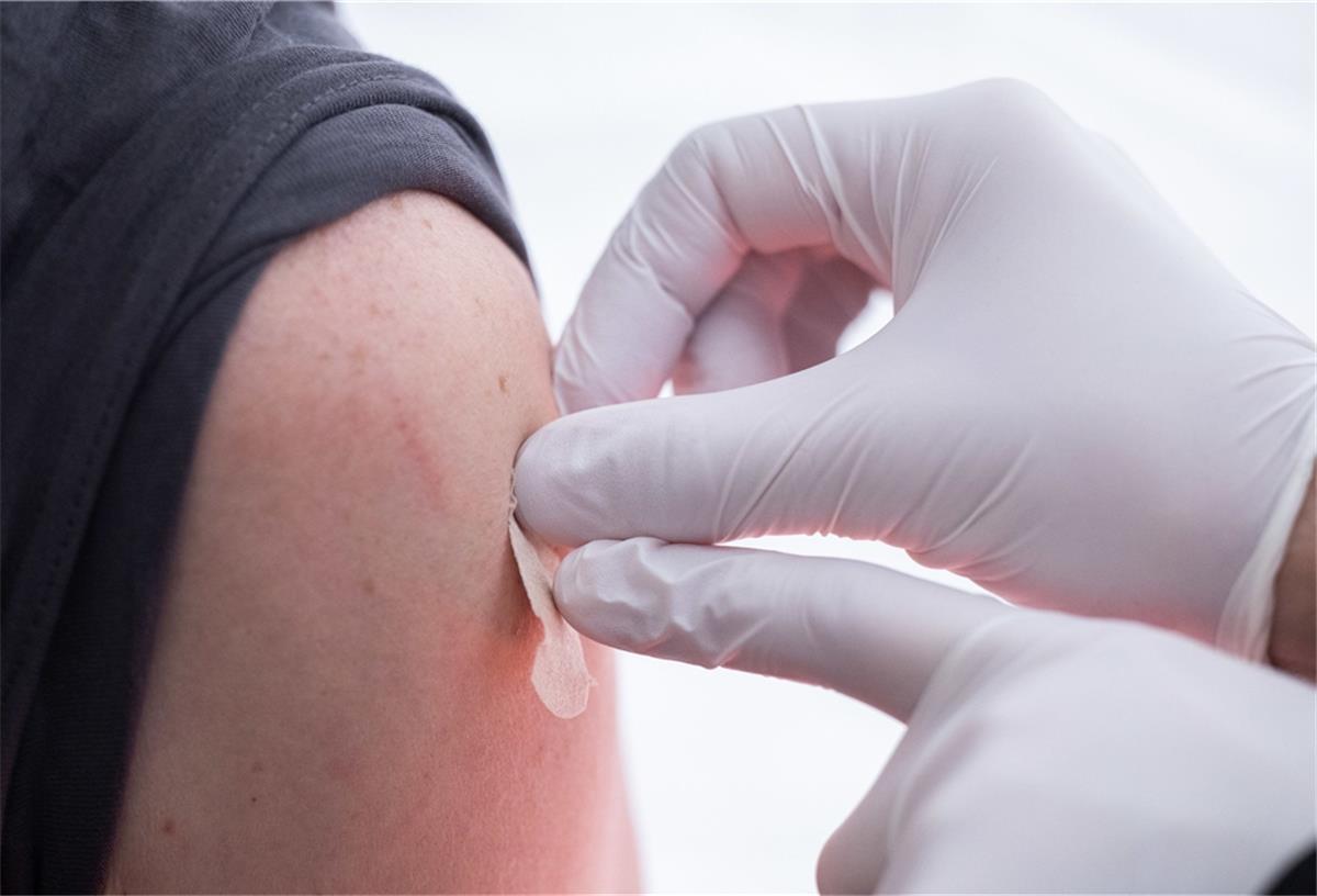 Verdi befürchtet wegen Impfpflicht Kündigungen in Kliniken Eine geimpfte Person bekommt vom Arzt ein Pflaster auf die Nadeleinstichstelle am Oberarm.