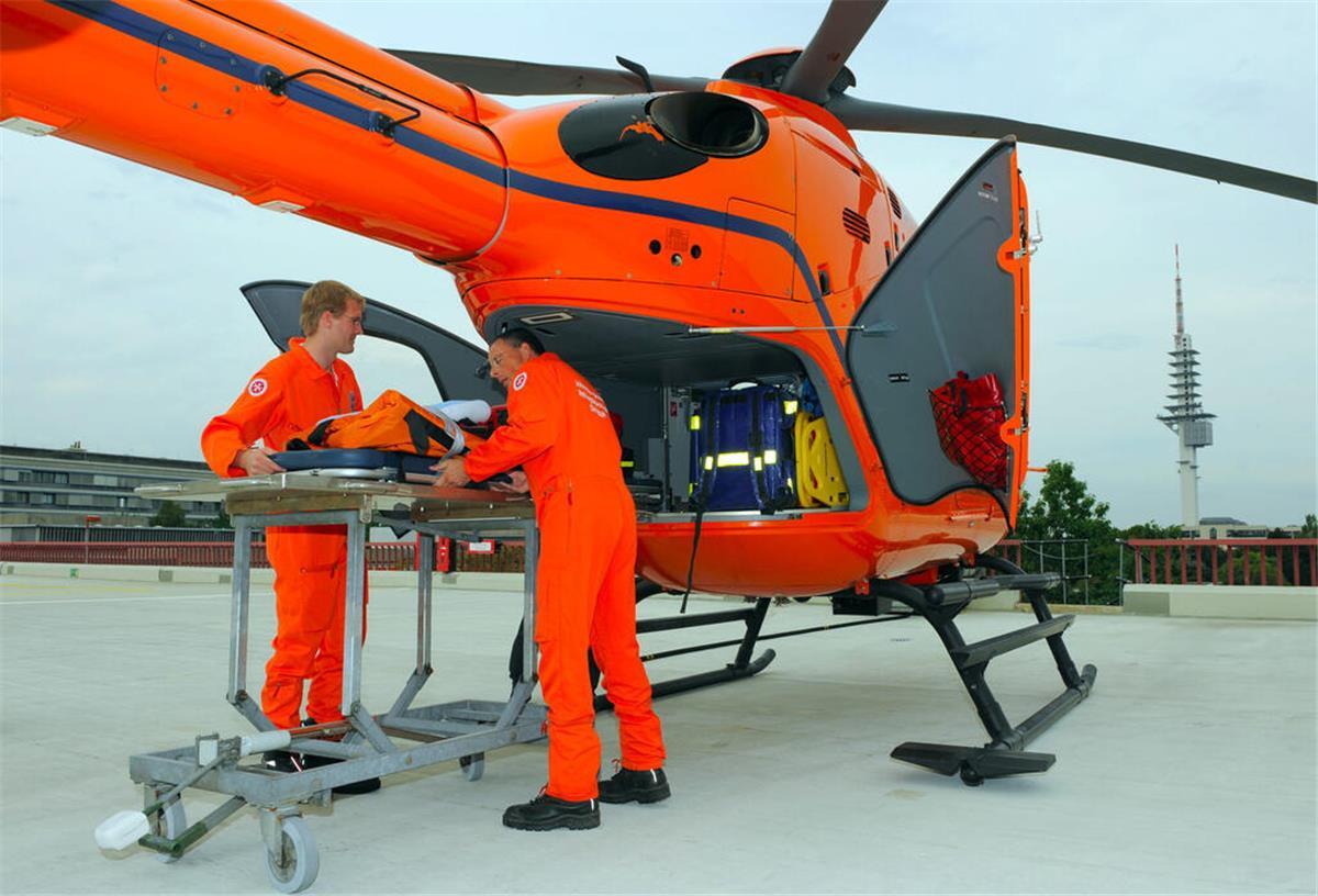 Johanniter Niedersachsen: Rettungshubschrauber immer wichtiger Zwei Rettungssanitäter ziehen eine Trage aus dem Rettungshubschrauber Christoph 4 auf dem Landeplatz der Medizinischen Hochschule Hannover (MHH).