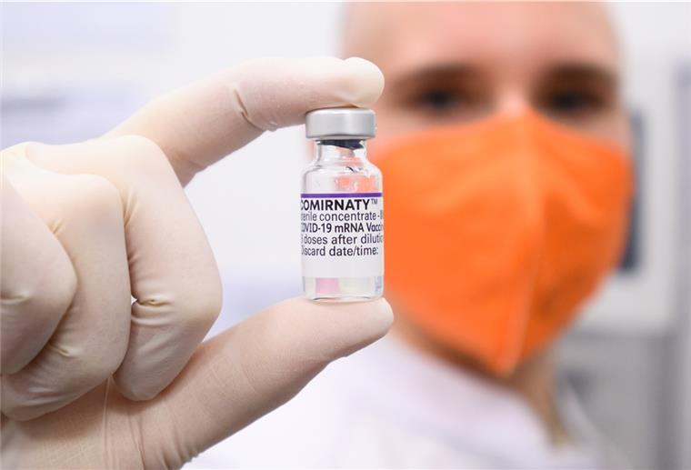 Cuxhaven und Bad Bederkesa: Unbrauchbarer Impfstoff verabreicht Ein Biontech Impfstoff-Fläschchen wird von jemandem mit orangener Maske in die Kamera gehalten.