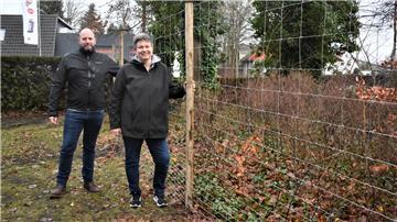 Der Kampf gegen die unerwünschten Rehe auf dem Langener Friedhof soll endlich ein Ende haben: Ortsbürgermeister Sascha Kuntzmann und Anja Heins von der Stadt Geestland freuen sich, dass der neue Wildzaun steht.