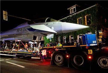 Ein Schwertransporter fährt mit einem Kampfflugzeug vom Typ Eurofighter Typhoon der Luftwaffe durch eine Straße.