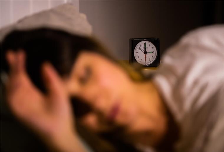 Das Gedankenkarussell stoppen: Einschlafen mit einer simplen Technik Eine Frau liegt im Bett.