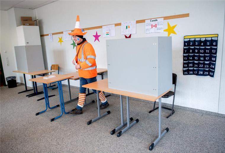 Dinosaurier, Elvis und Co. stürmen das Wahllokal! Der kostümierte Wähler Henrik verlässt in einem Wahllokal nach der Stimmabgabe den Sichtschutz der Wahlkabine.