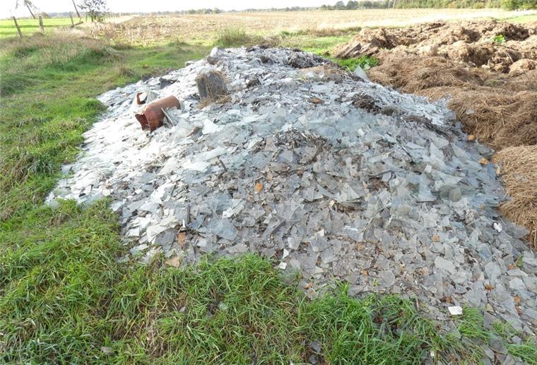Neben einem Misthaufen auf einem Feld liegt ein Haufen mit Abfall aus Schutt und Scherben.
