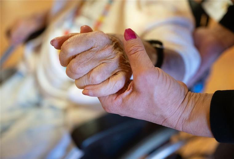 Bremerhaven kämpft mit Pflegekräftemangel: Deshalb werden Azubis trotzdem abgewiesen Eine Pflegekraft hält die Hand einer Pflegebedürftigen.