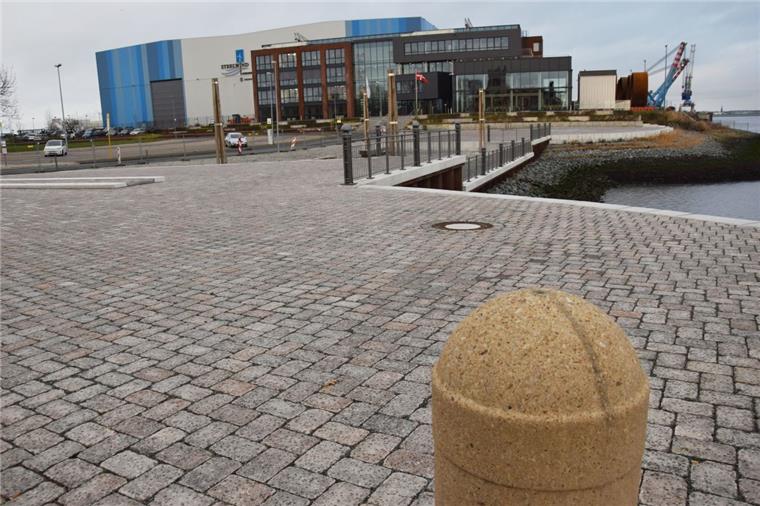 Der mit rauen Steinen gepflasterte Platz am Blexer Fähranleger verbindet das moderne Verwaltungsgebäude von Steelwind und das Weserschlösschen, moderne Industriearchitektur der heutigen Zeit und Historismus.