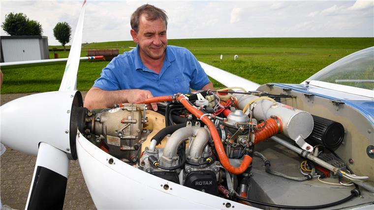Ein Mann überprüft den Motor eines Flugzeugs.