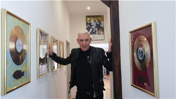 Der Musiker H.P. Baxxter steht in einem Flur in seinem Musikstudio neben zahlreichen goldenen Schallplatten.