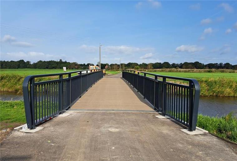 Der Radweg ist eröffnet: Der Schiffdorfer Bürgermeister Henrik Wärner (CDU) durchtrennt symbolisch eine Kette auf der neuen Brücke über die Alte Geeste.