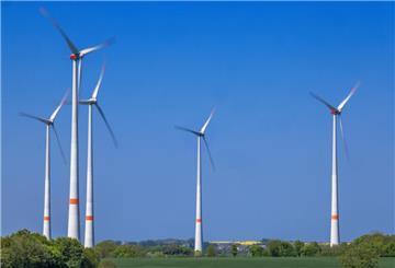 Mehrere Windräder stehen auf einem Feld bei blauem Himmel