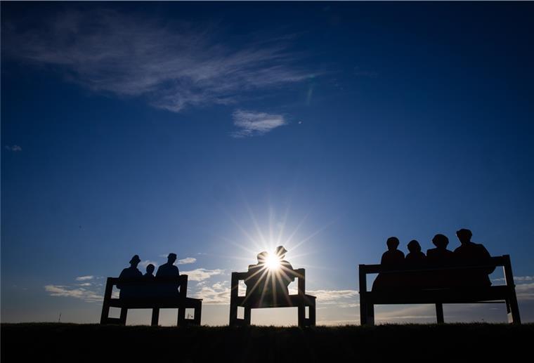 Niedersachsen und Bremen dürfen sich auf sonniges Wetter freuen Drei Bänke mit Rückenlehnen in Form von sitzenden Menschen stehen auf dem Deich am Hafen von Büsum.
