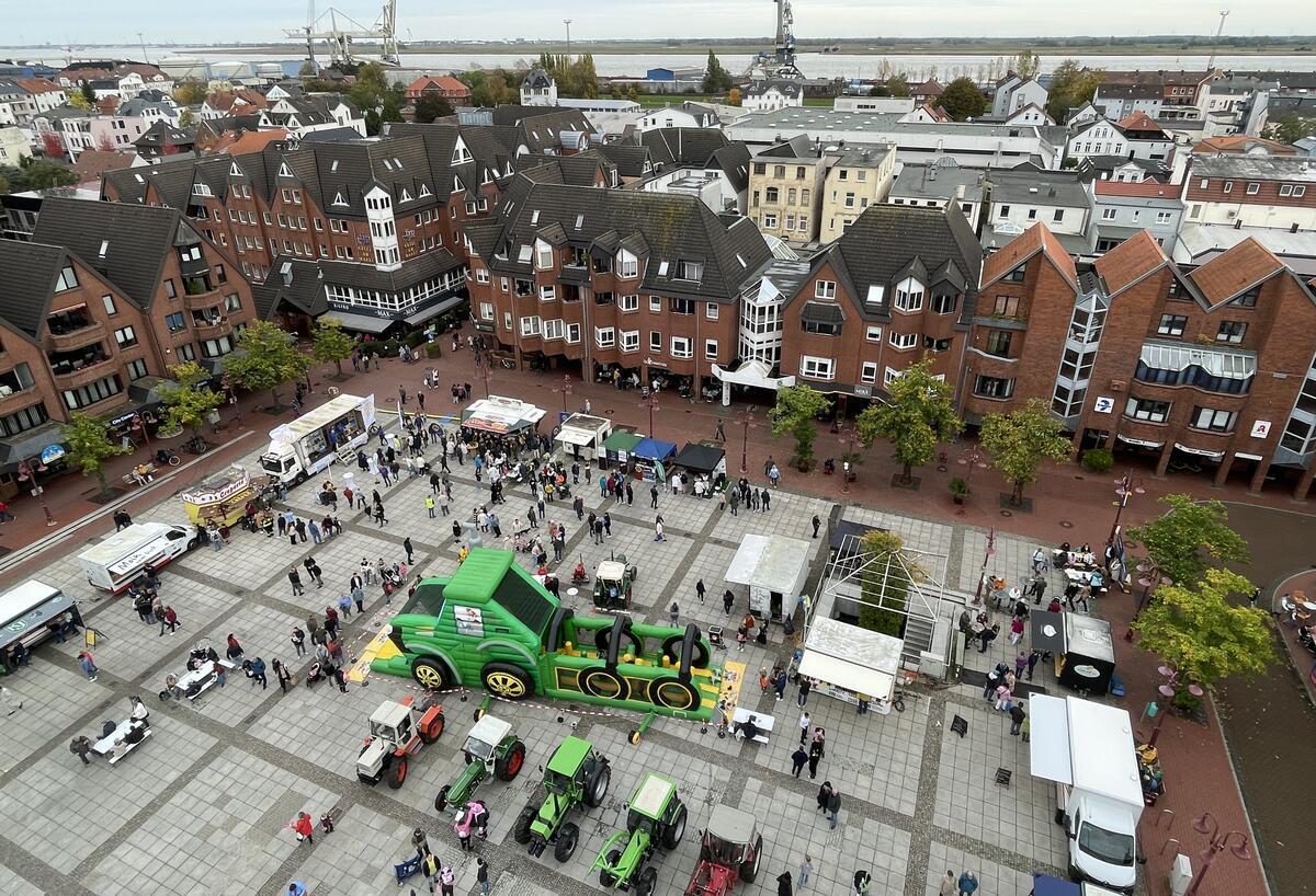 Nordenham lädt ein zum Ochsenmarkt Der Ochsenmarkt auf dem Nordenhamer Marktplatz aus der Vogelperspektive. In der Mitte steht eine große Hüpfburg in Form eines Trekkers. Drumherum stehen echte Trekker und Marktbuden.