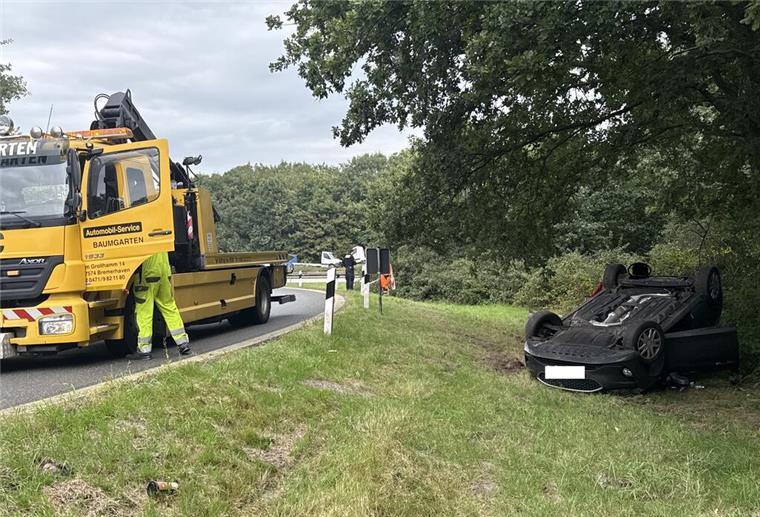 Ein verunglücktes Auto liegt in einer Autobahnabfahrt auf dem Dach.
