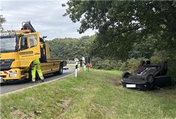 Ein verunglücktes Auto liegt in einer Autobahnabfahrt auf dem Dach.