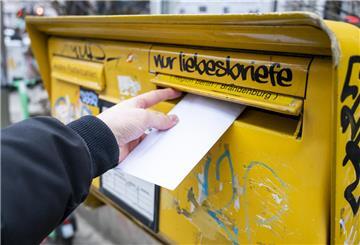 Ein Mann wirft einen Brief in einen Briefkasten