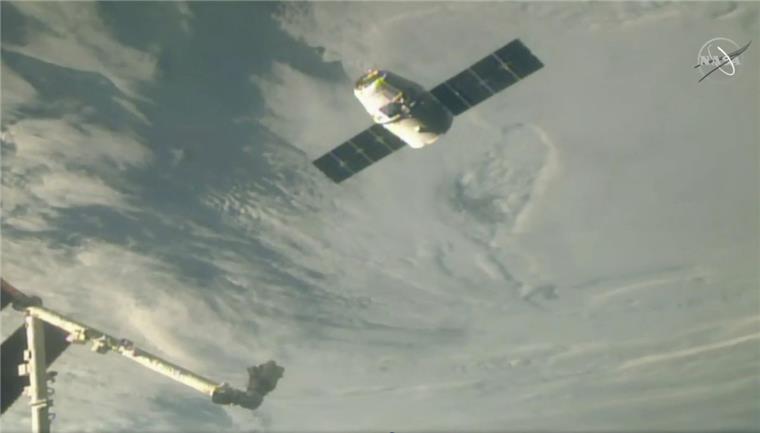 Der  Raumfrachter Dragon nähert sich einem Roboterarm zum Andocken an die Internationale Raumstation ISS. Der Frachter ist unter anderem mit einem Weihnachtsmenü beladen. 