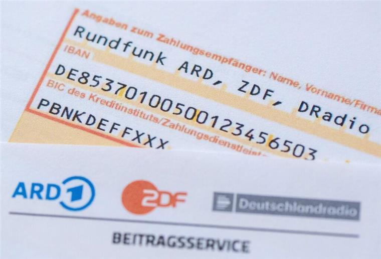 Eine schriftliche Banküberweisung liegt auf dem GEZ-Dokument.