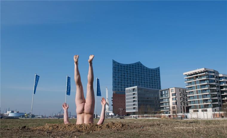 Russischer Künstler gräbt sich nackt und kopfüber vor Elbphilharmonie ein Der russische Konzeptkünstler Andrey Kuzkin steckt vor der Elbphilharmonie kopfüber und unbekleidet in der Erde.