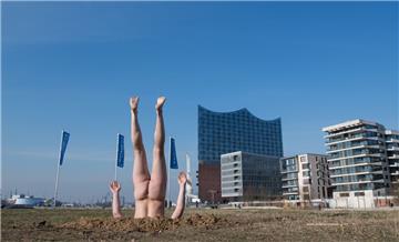 Der russische Konzeptkünstler Andrey Kuzkin steckt vor der Elbphilharmonie kopfüber und unbekleidet in der Erde.



 