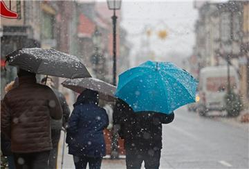 Menschen gehen mit Regenschirm bei Schneeregen am Montagvormittag durch die Innenstadt von Wernigerode.