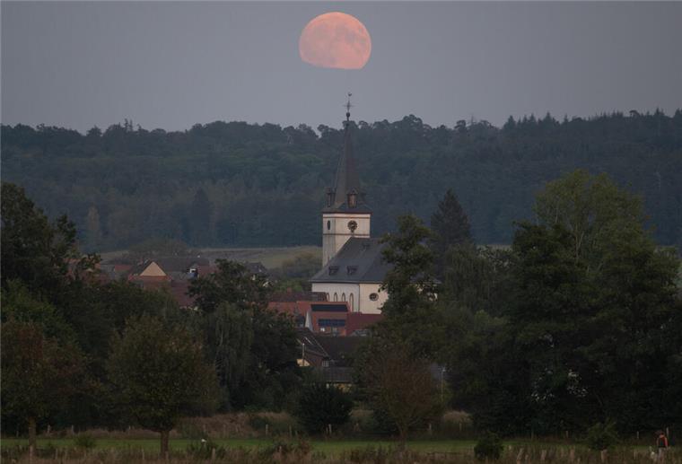 Supermond und partielle Mondfinsternis: So sah das Spektakel am Nachthimmel aus Der Supermond geht hinter der Kirche von Wehrheim im hessischen Taunus auf.