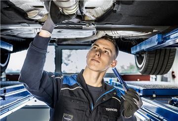 Ein Mitarbeiter vom TÜV repariert ein Auto. Der TÜV nimmt ältere Autos aufs Korn. Für sie sollen bald andere Regeln gelten.