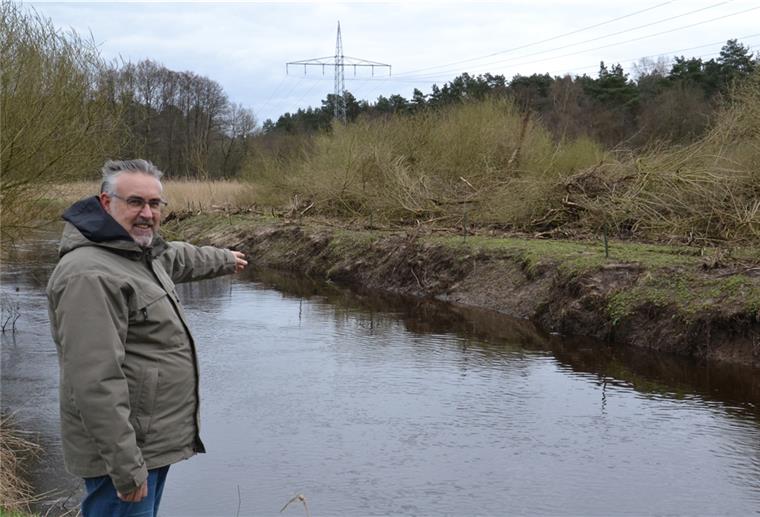 Der Vorsitzende des Angelsportvereins, Dirk Glaß, steht am Ufer der Oste und zeigt auf die gefällten Bäume