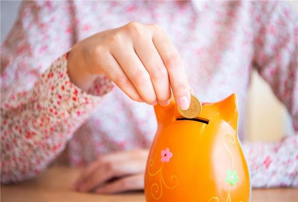 Eine Frau wirft eine Münze in eine Spardose.