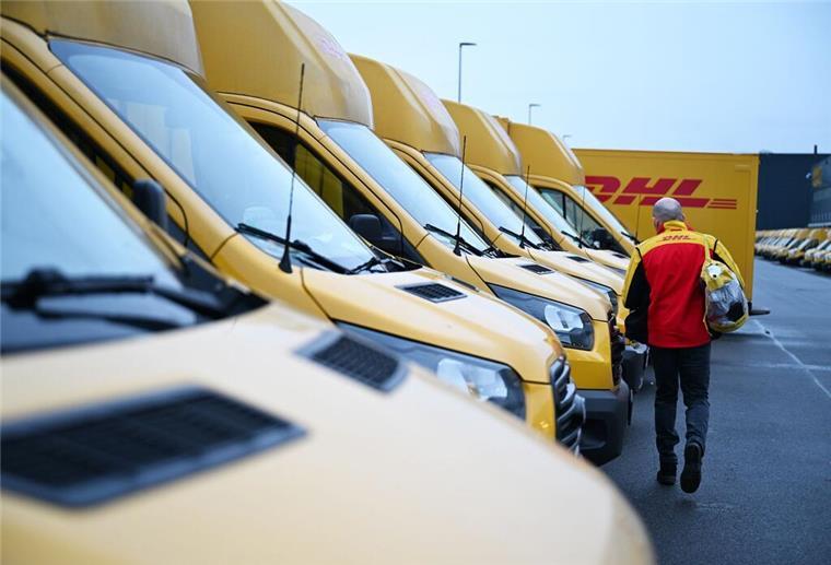 Ein Paketbote von DHL geht zu seinem Elektrofahrzeug, mit dem er wenig später seine Zustelltour beginnt.