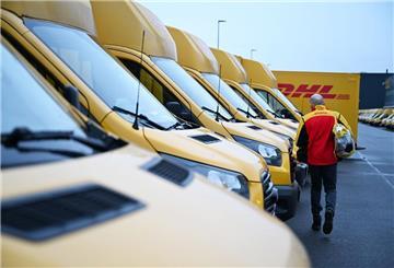 Ein Paketbote von DHL geht zu seinem Elektrofahrzeug, mit dem er wenig später seine Zustelltour beginnt.