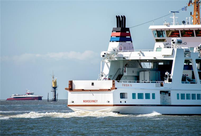 Das Fährschiff „Frisia IV“ ist im Wattenmeer vor der Insel Norderney unterwegs, während sich im Hintergrund der Katamaran MS „Adler Rüm Hart“ der Insel nähert.