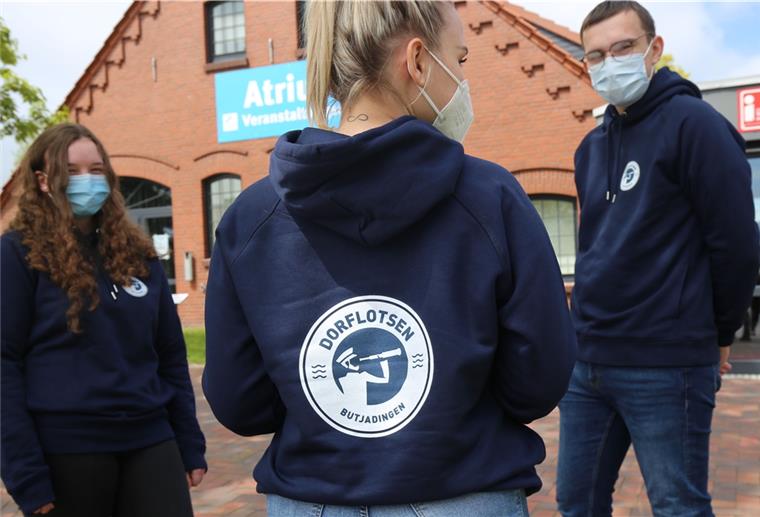 Die Auszubildenden des Tourismus-Service Butjadingen Theresa Schmidt, Kitana Petz und Moritz Wickner präsentieren die neuen Hoodies samt Dorflotsen-Logo - die gehören zum Dorflotsen-Team.