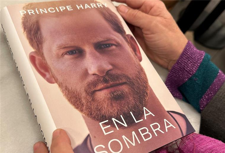 Ein Prinz packt aus: Details aus Harry-Biografie schocken Briten Eine Frau hält ein Exemplar Autobiografie des britischen Prinzen Harry.