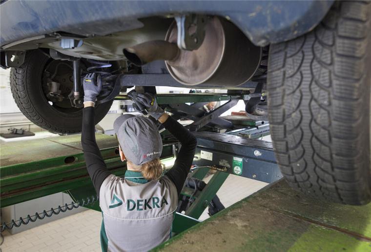 Eine KFZ-Ingenieurin kontrolliert in einer Dekra-Werkstatt ein Fahrzeug bei einer Hauptuntersuchung